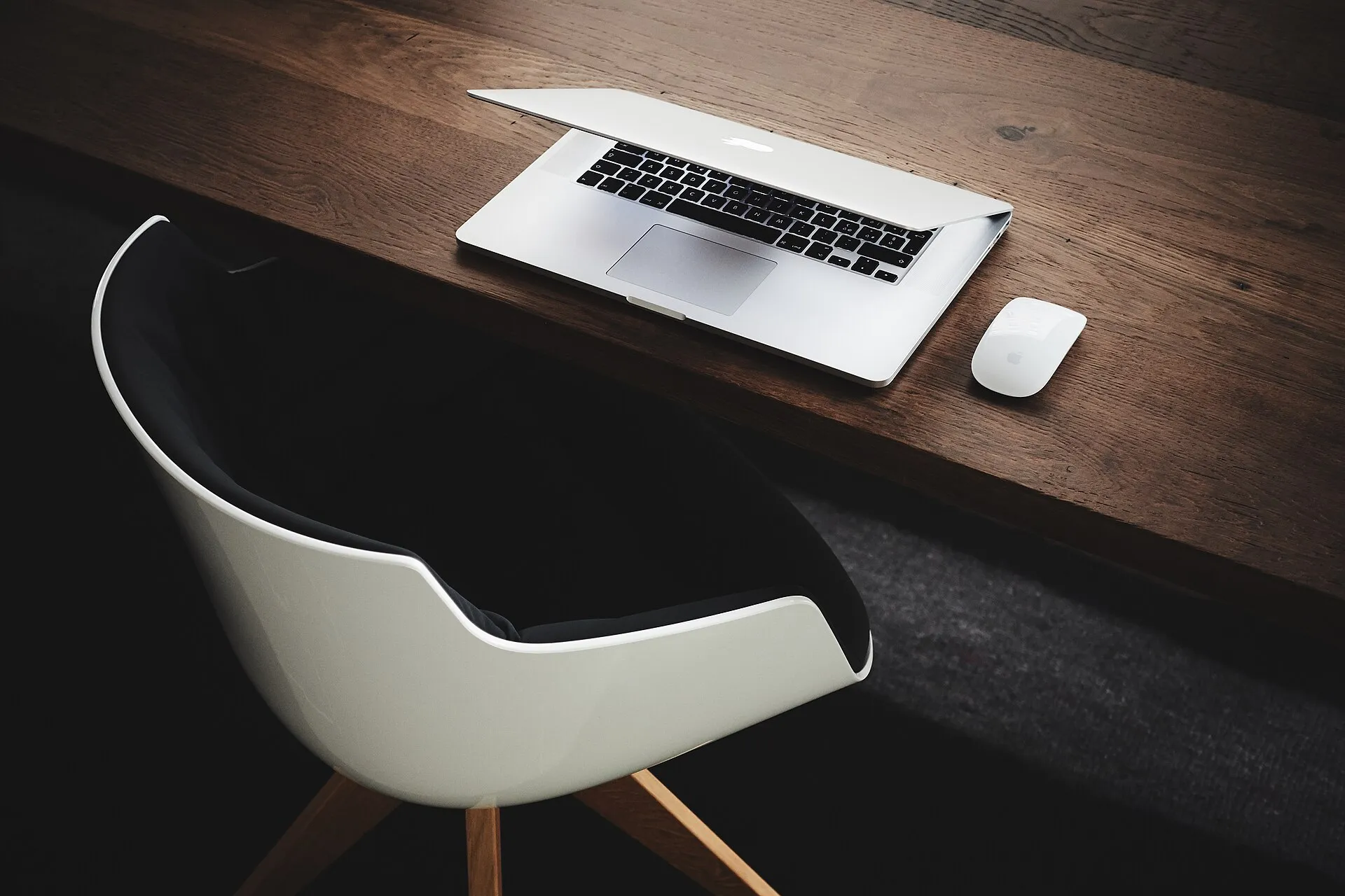 An empty desk in a quiet modern office with a laptop and a cup of coffee