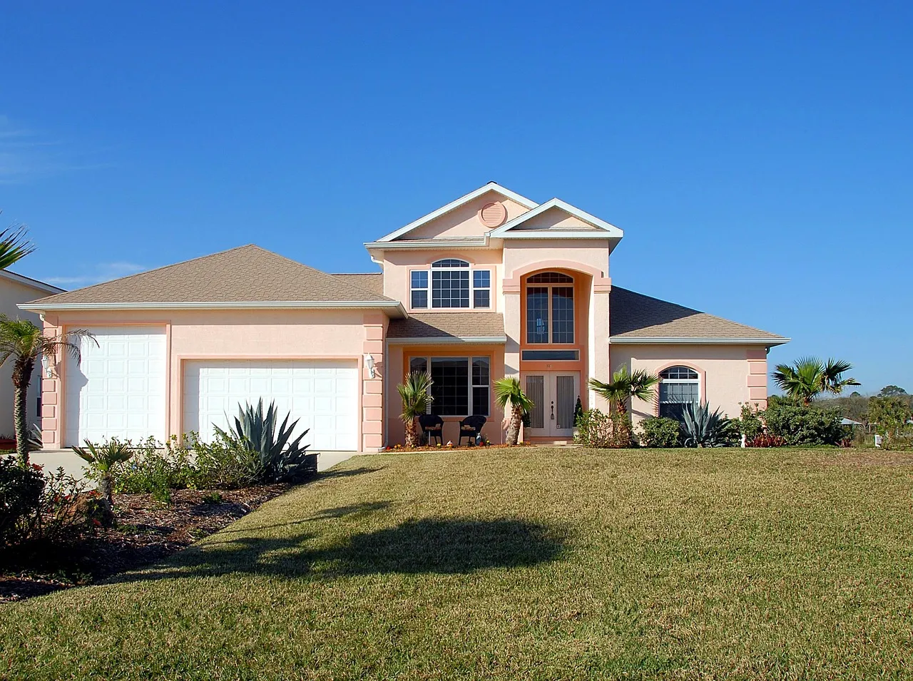 A suburban house with a green lawn under a blue sky, representing a primary residence