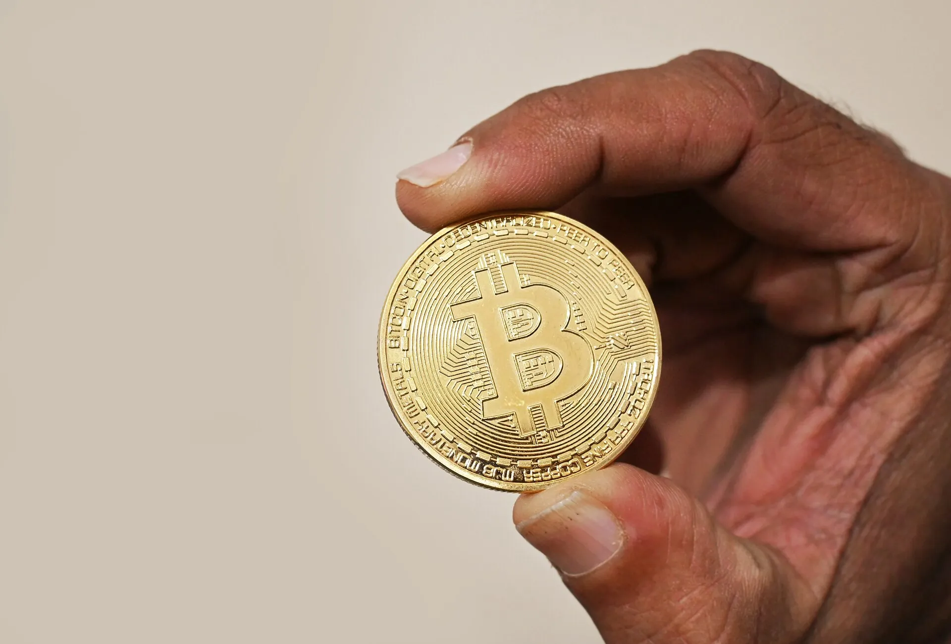 A hand holding a physical bitcoin coin