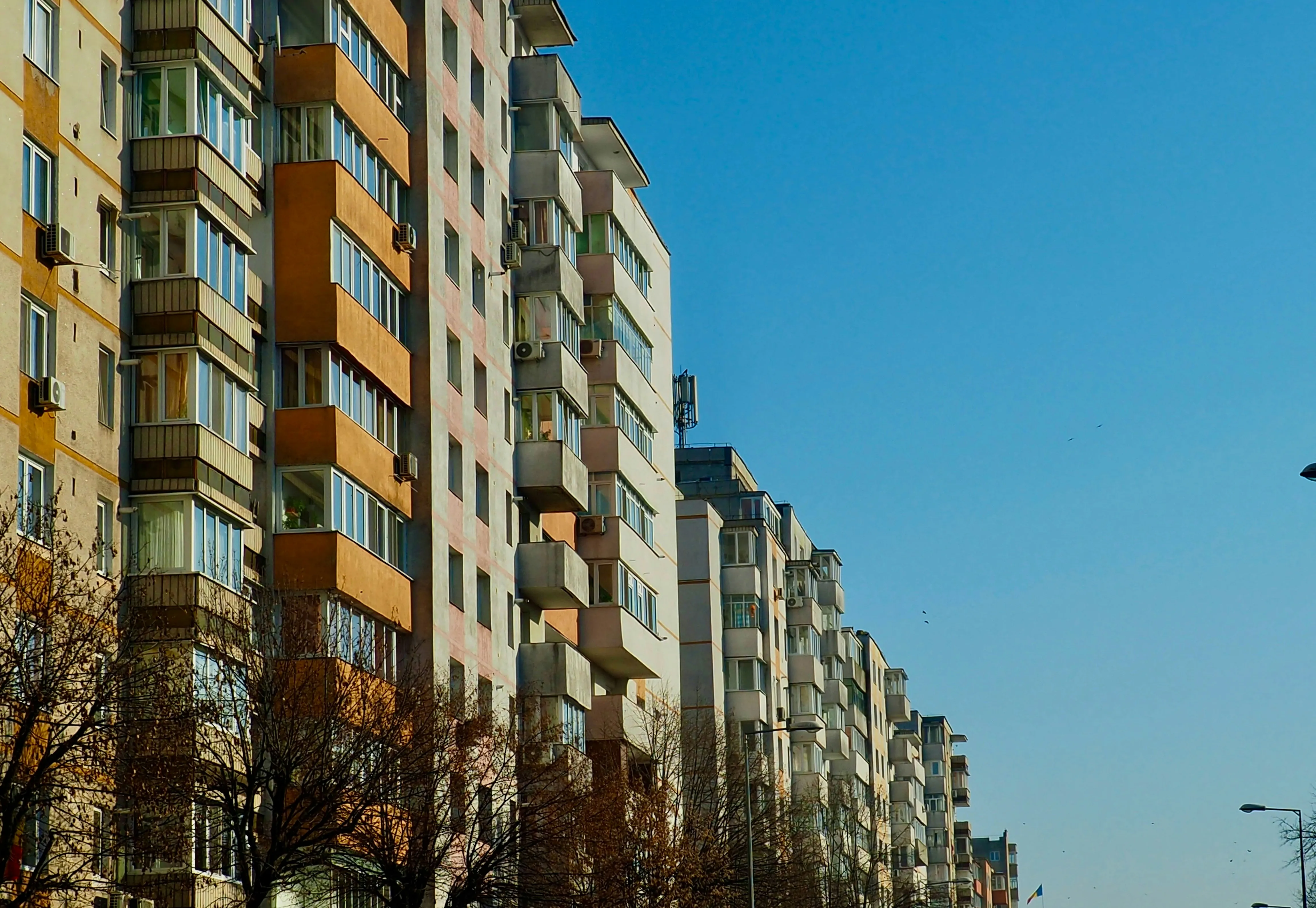 A row of apartment buildings with balconies lining a city street under a clear sky, representing rental housing